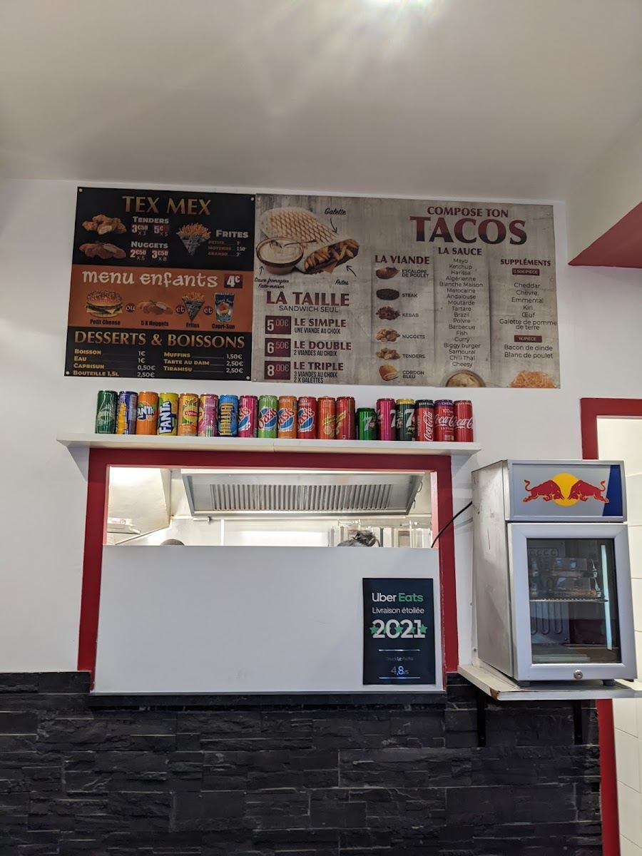 Comptoir du snack avec le tableau des menus tacos et tex-mex, canettes alignées