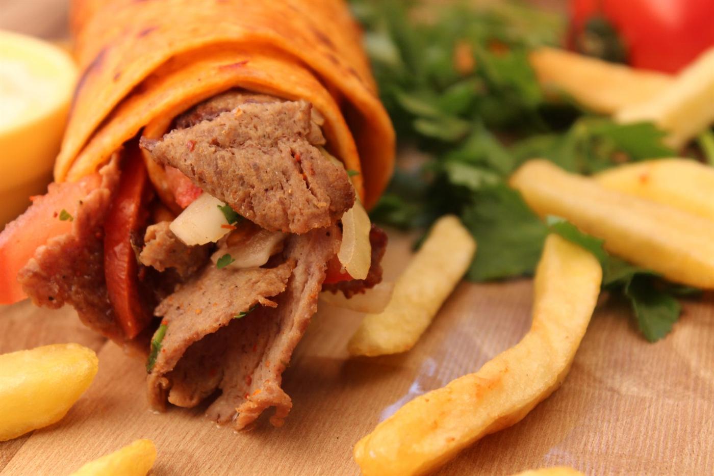 Kebab roulé dans une galette, viande, oignons et frites
