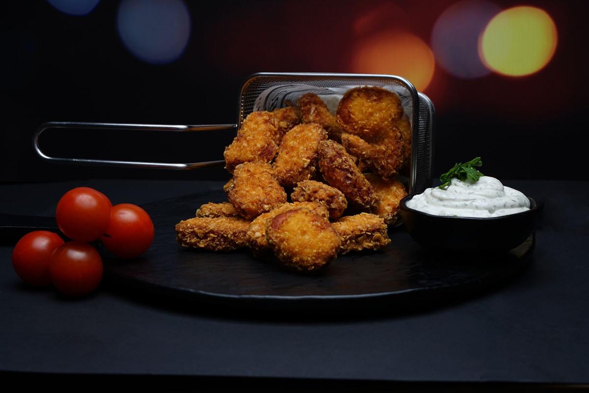 Nuggets dorés dans un panier avec une sauce blanche et des tomates cerises