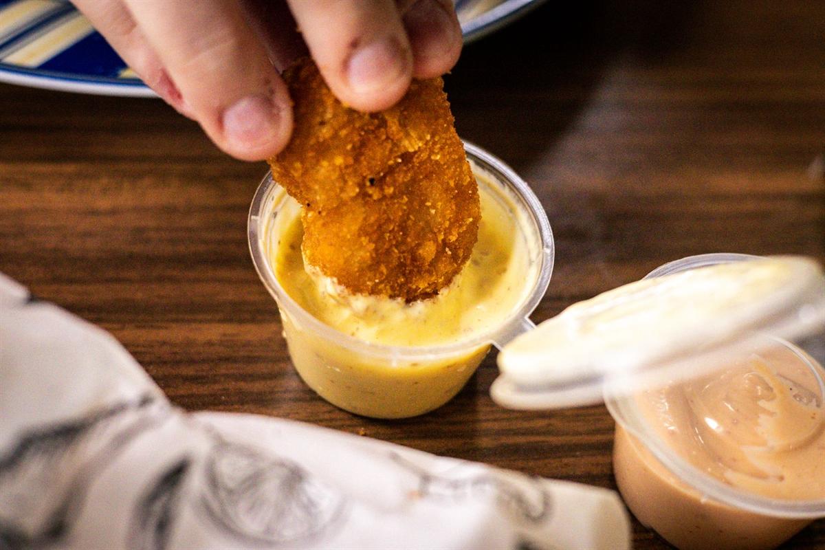 Un tender plongé dans une sauce jaune
