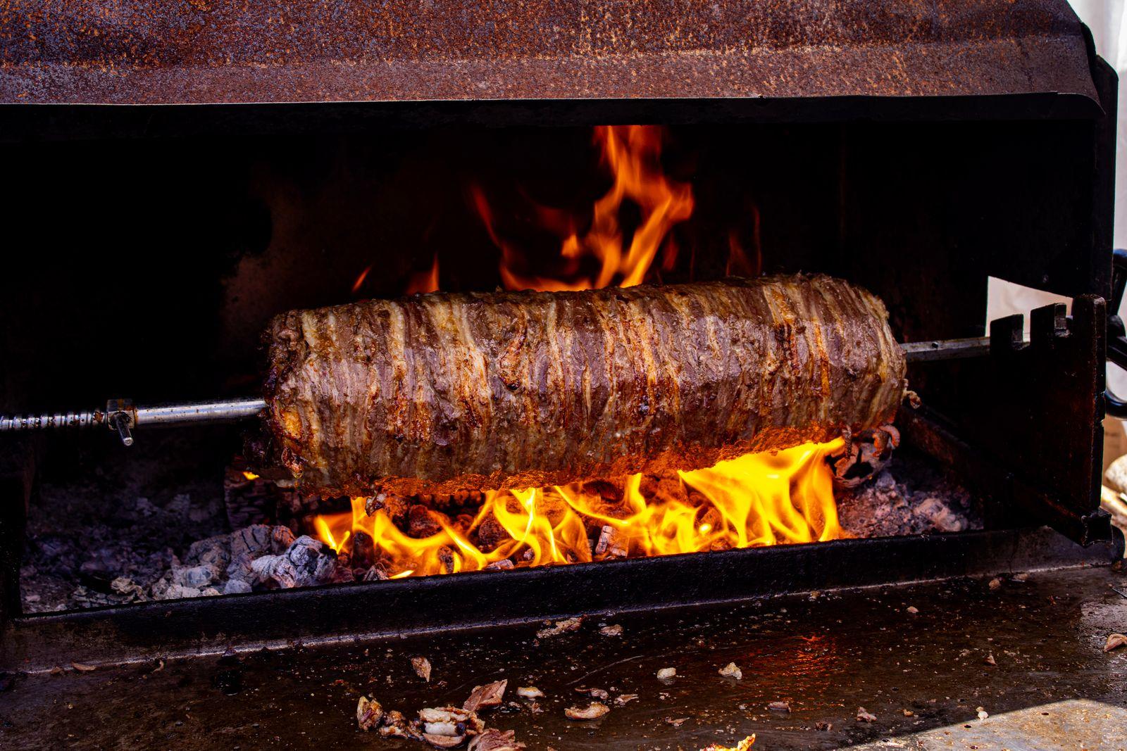 Broche de kebab doré qui tourne au-dessus des braises