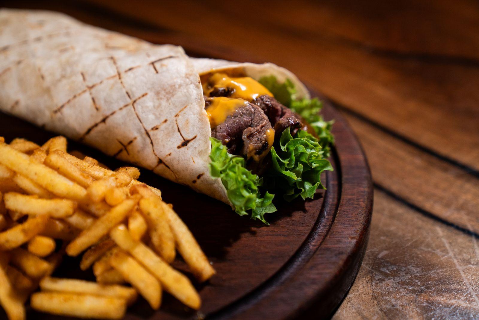 Tacos grillé coupé en deux, garni de viande, fromage et frites