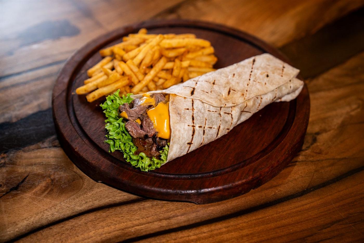 Tacos grillé et frites sur une assiette en bois